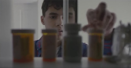 photo of teenage boy looking in medicine cabinet and reaching for perscription pills